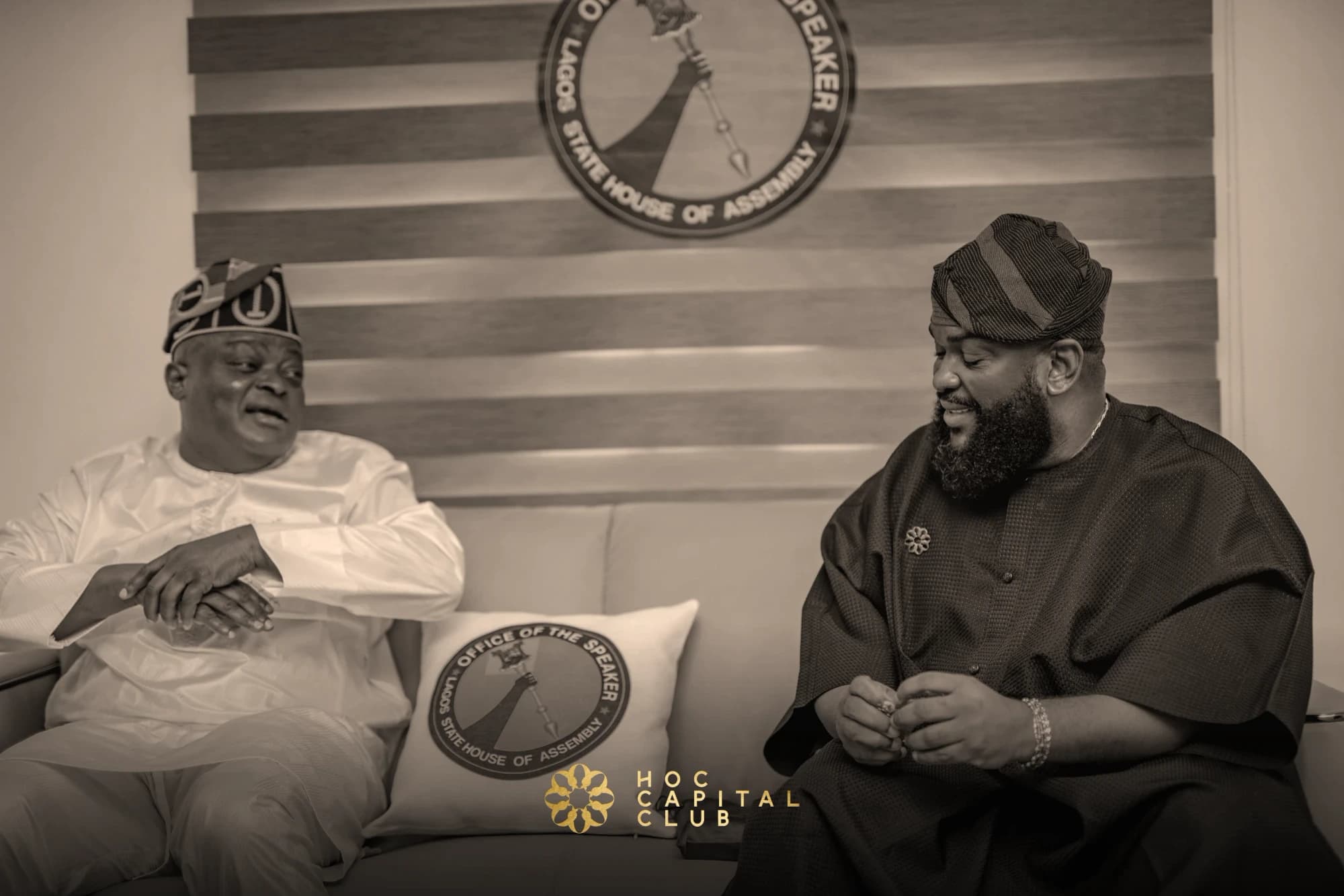 Two guests in conversation beneath the seal of the Office of the Speaker, Lagos State House of Assembly