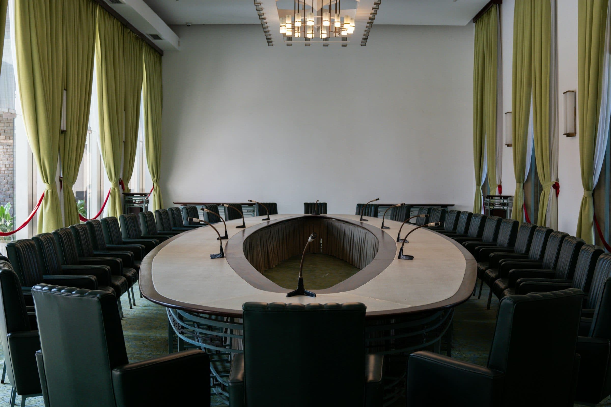 An empty round-table conference chamber with delegate microphones